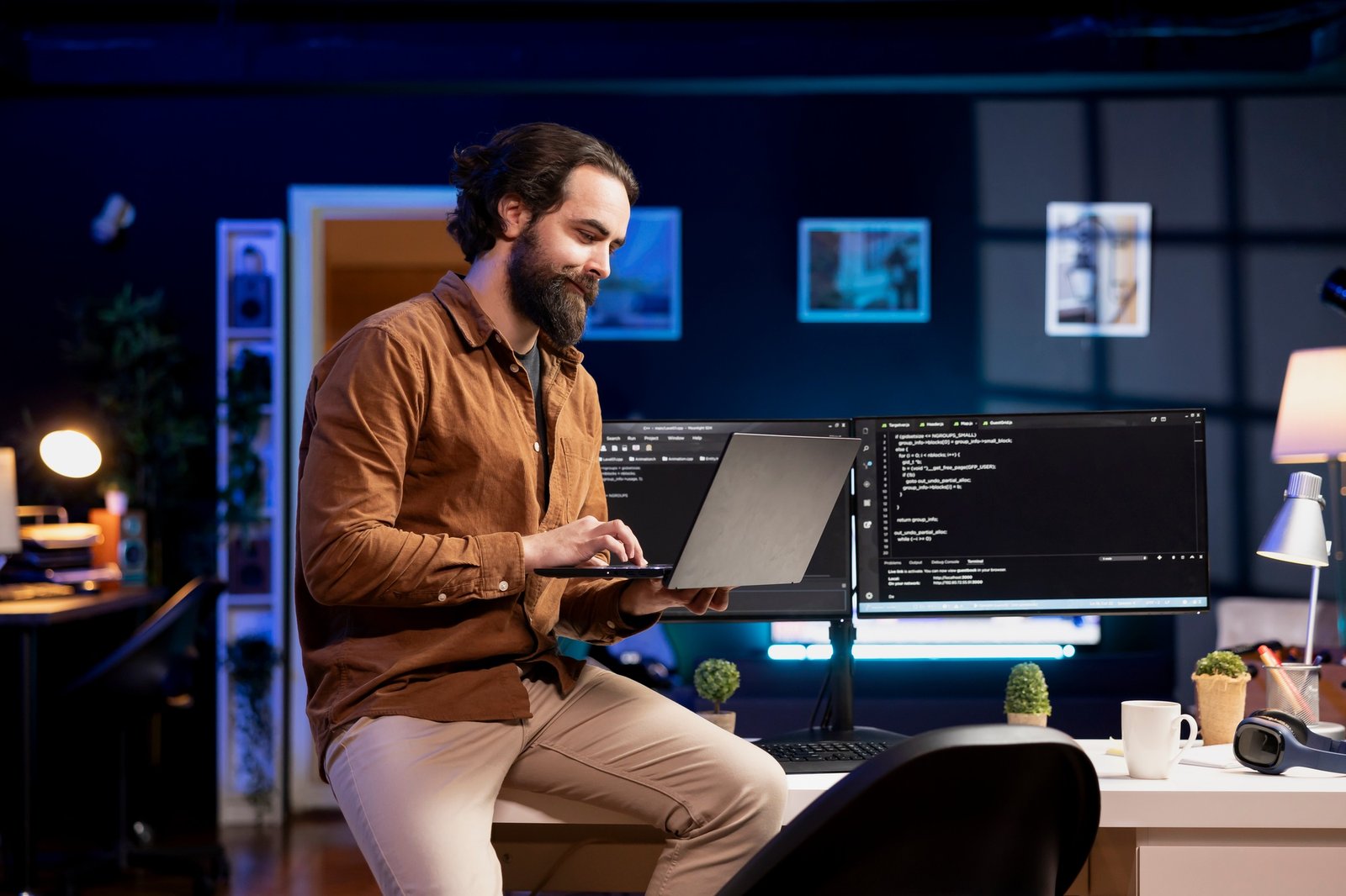 Happy man sitting on desk inspecting coding on notebook