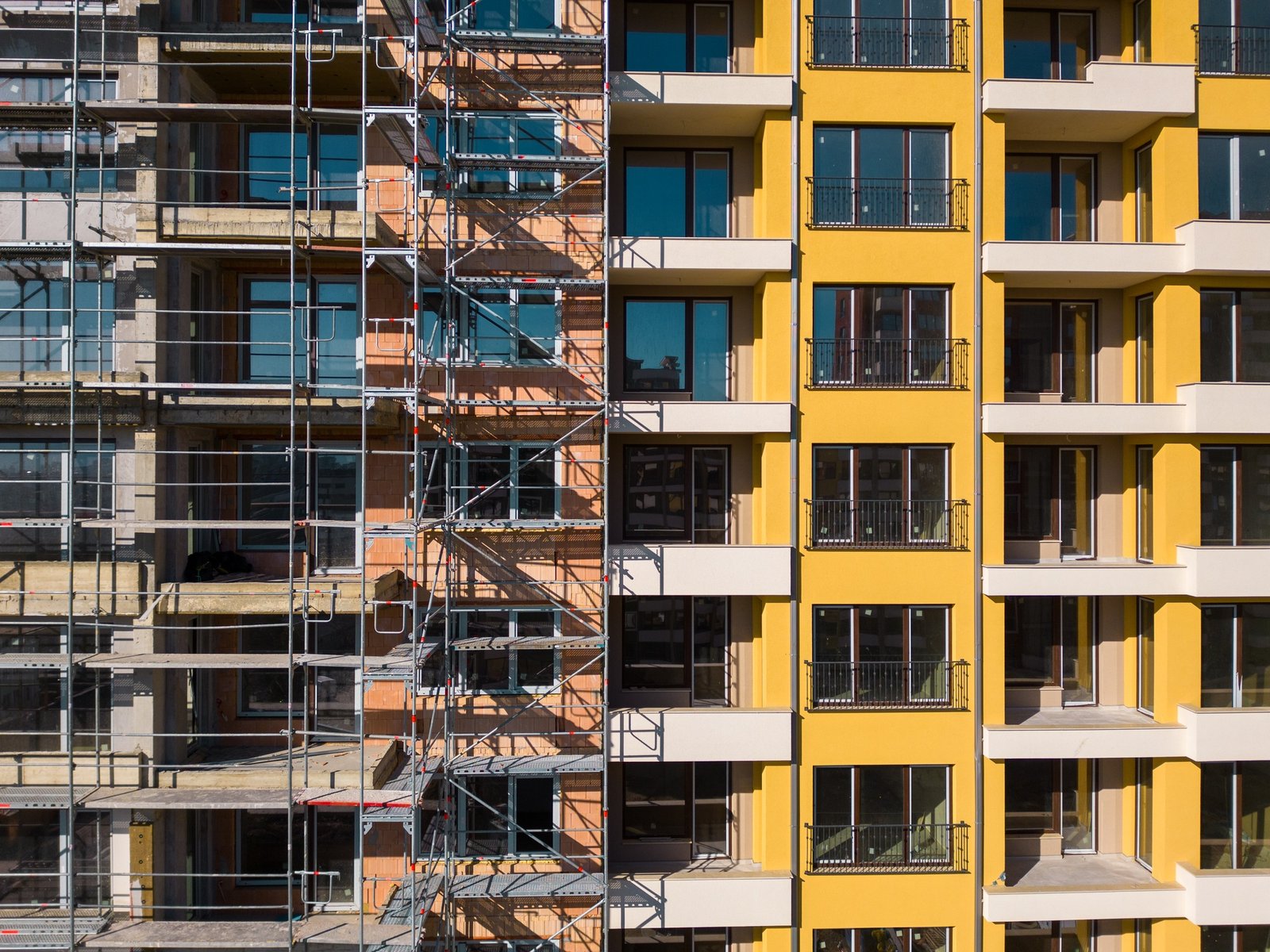 Drone flight along the facade of a modern apartment building under construction surrounded by