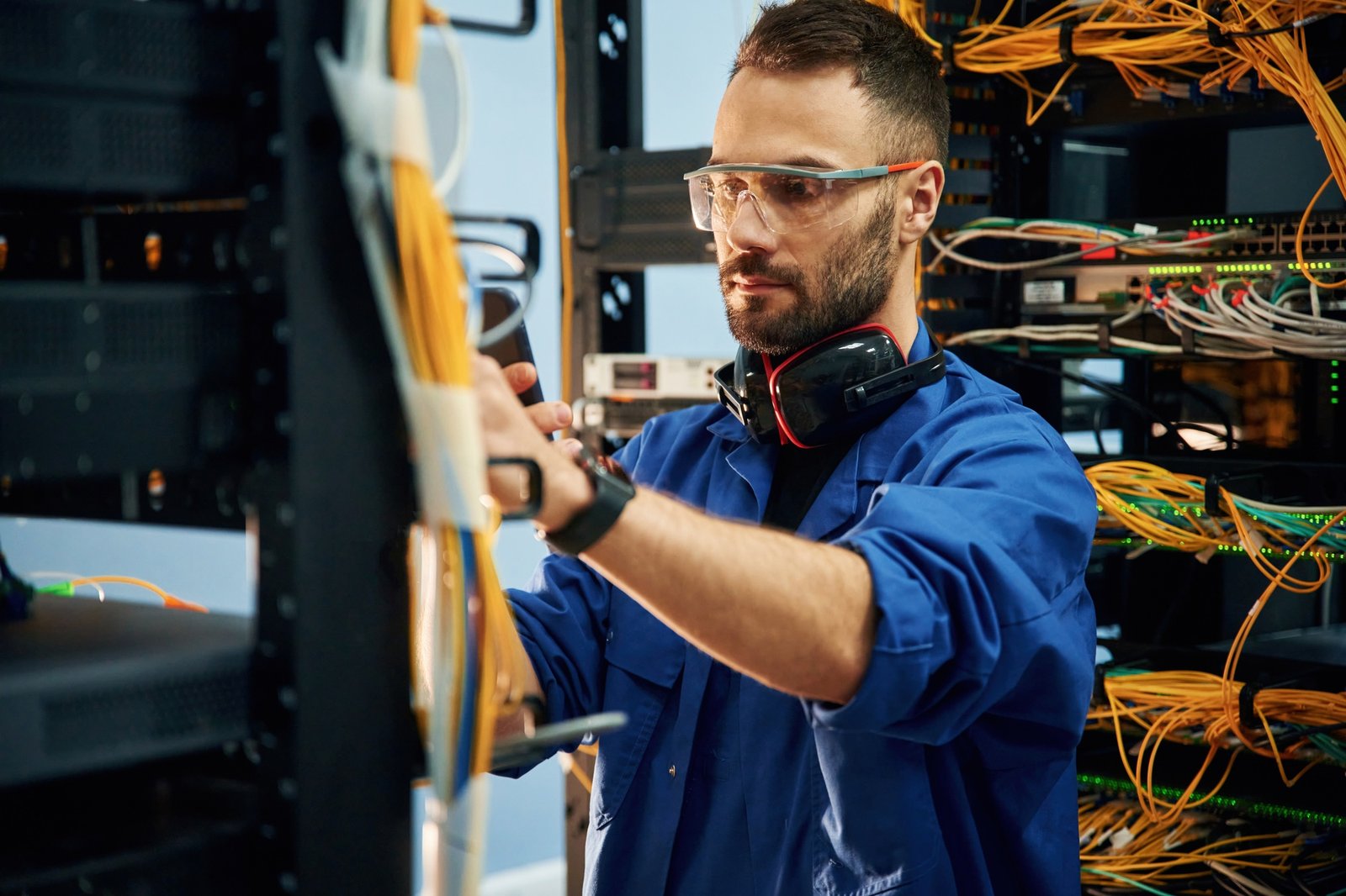 Restoring the internet connection. Young man is working with equipment and wires in server room