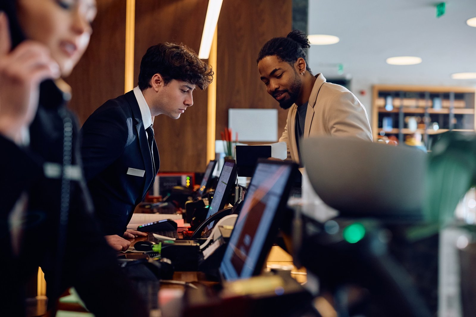 Smiling black man checking in at hotel reception desk.