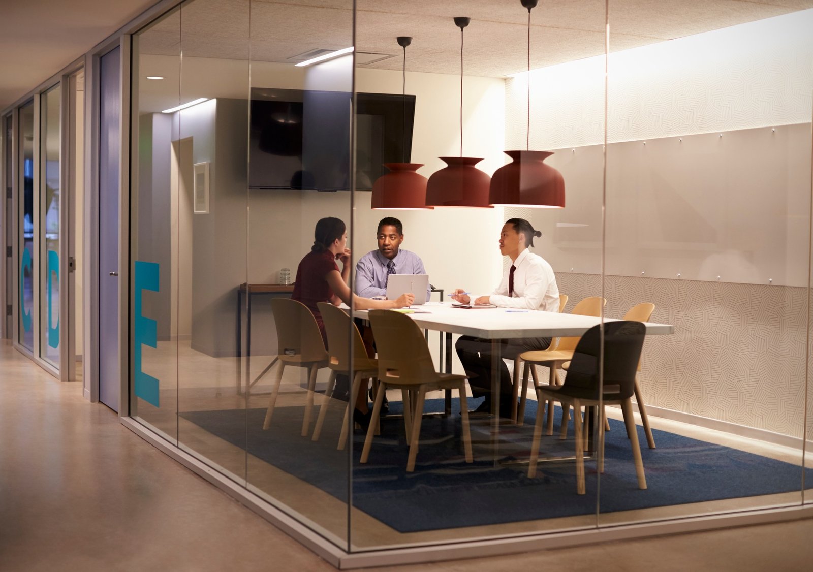 Three people in meeting cubicle at a big corporate business